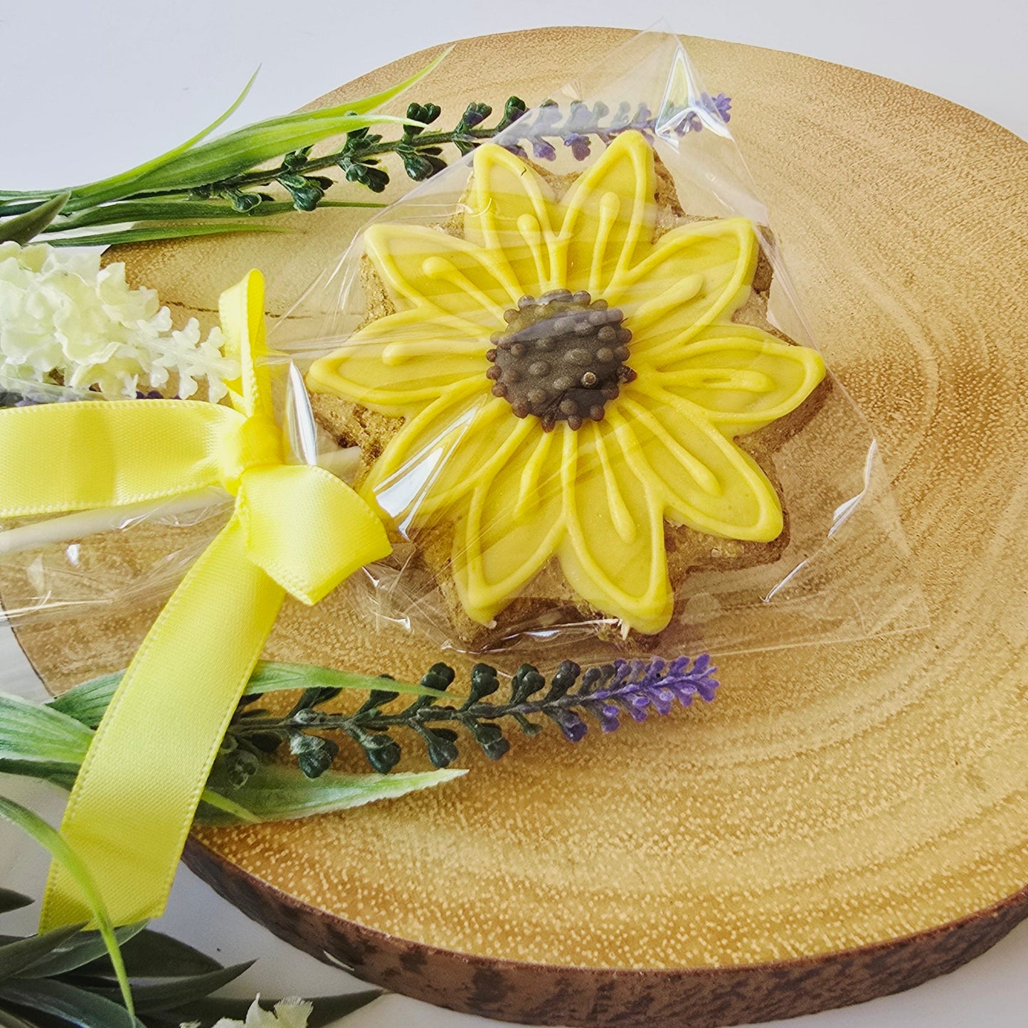 Sunflower cookie with yellow ribbon on a wooden board with flowers