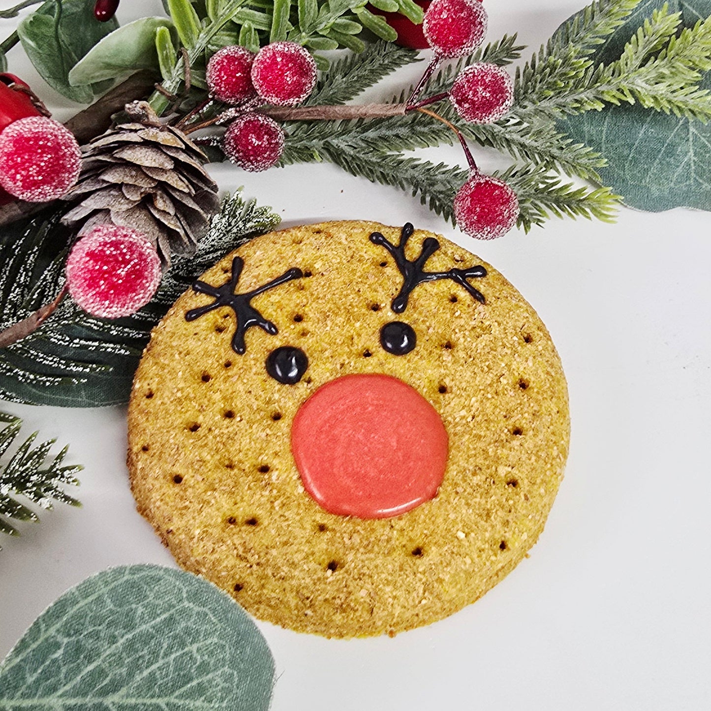 Decorative wreath with a reindeer cookie and greenery on a white background