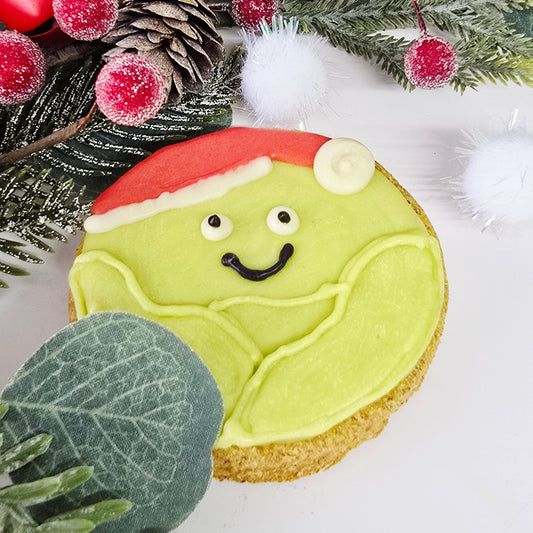 Decorative cookie with a face, surrounded by greenery and berries on a white background