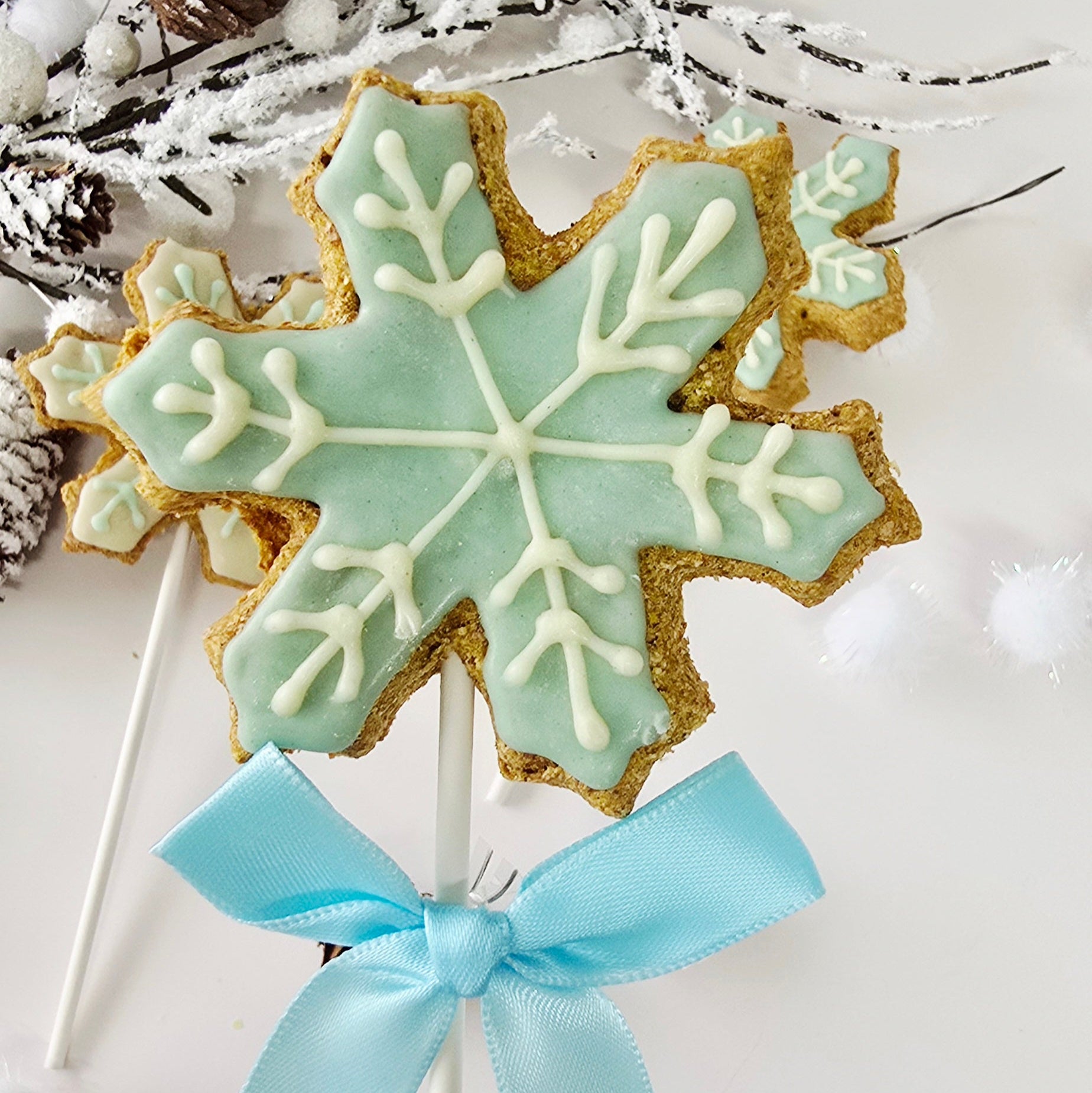 Decorative snowflake cookie on a stick with a blue ribbon against a white background