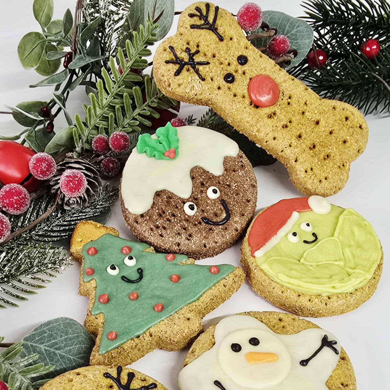 Decorative cookies shaped like a reindeer, Christmas tree, snowman, and pudding with festive decorations.