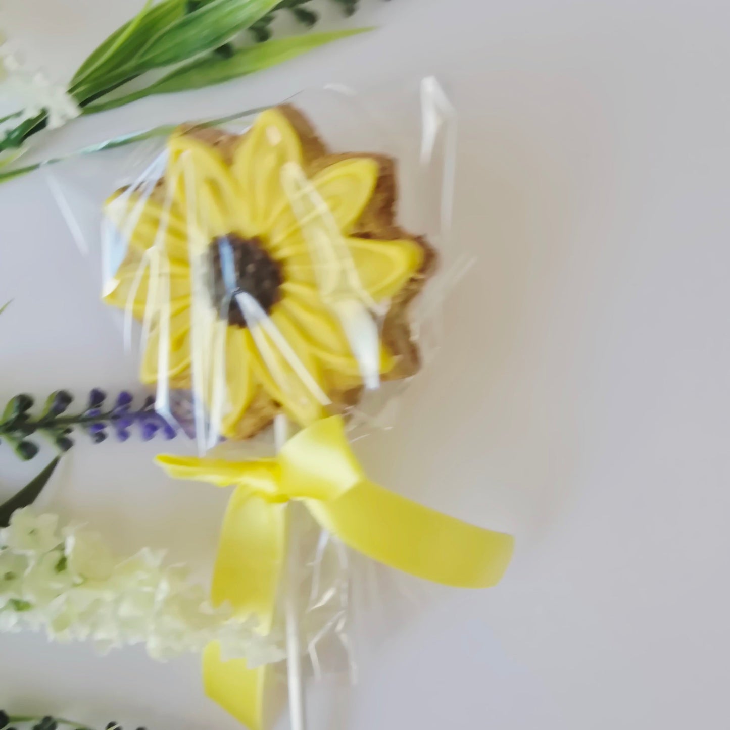 Sunflower-shaped cookie with a yellow ribbon on a white background