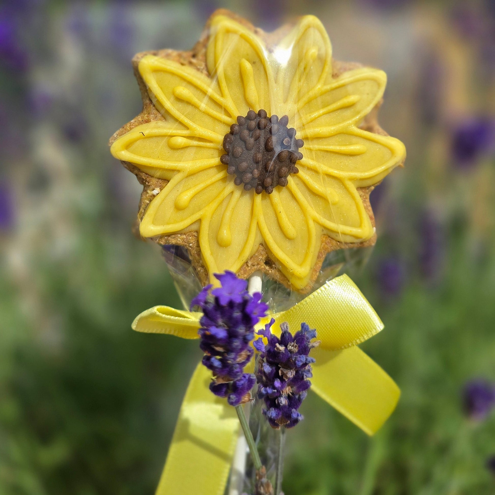 Yellow flower-shaped cookie with a yellow ribbon on a blurred floral background