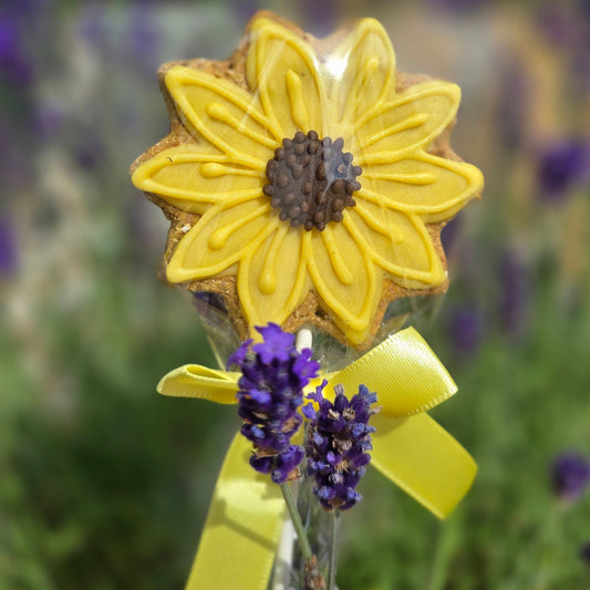 Yellow flower-shaped cookie with a yellow ribbon on a blurred floral background