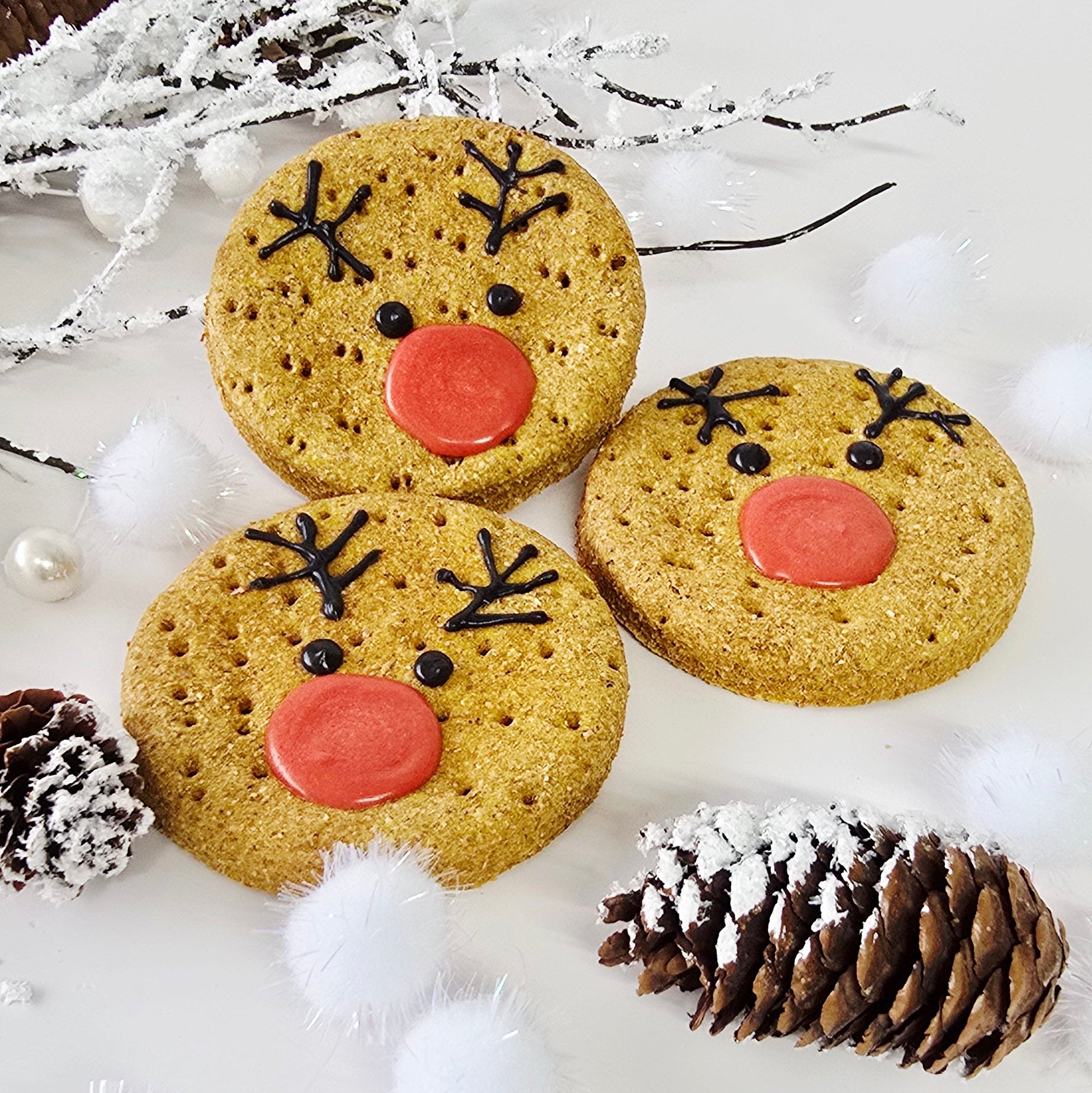 Three cookies with red centers and black patterns on a white surface with decorative elements.