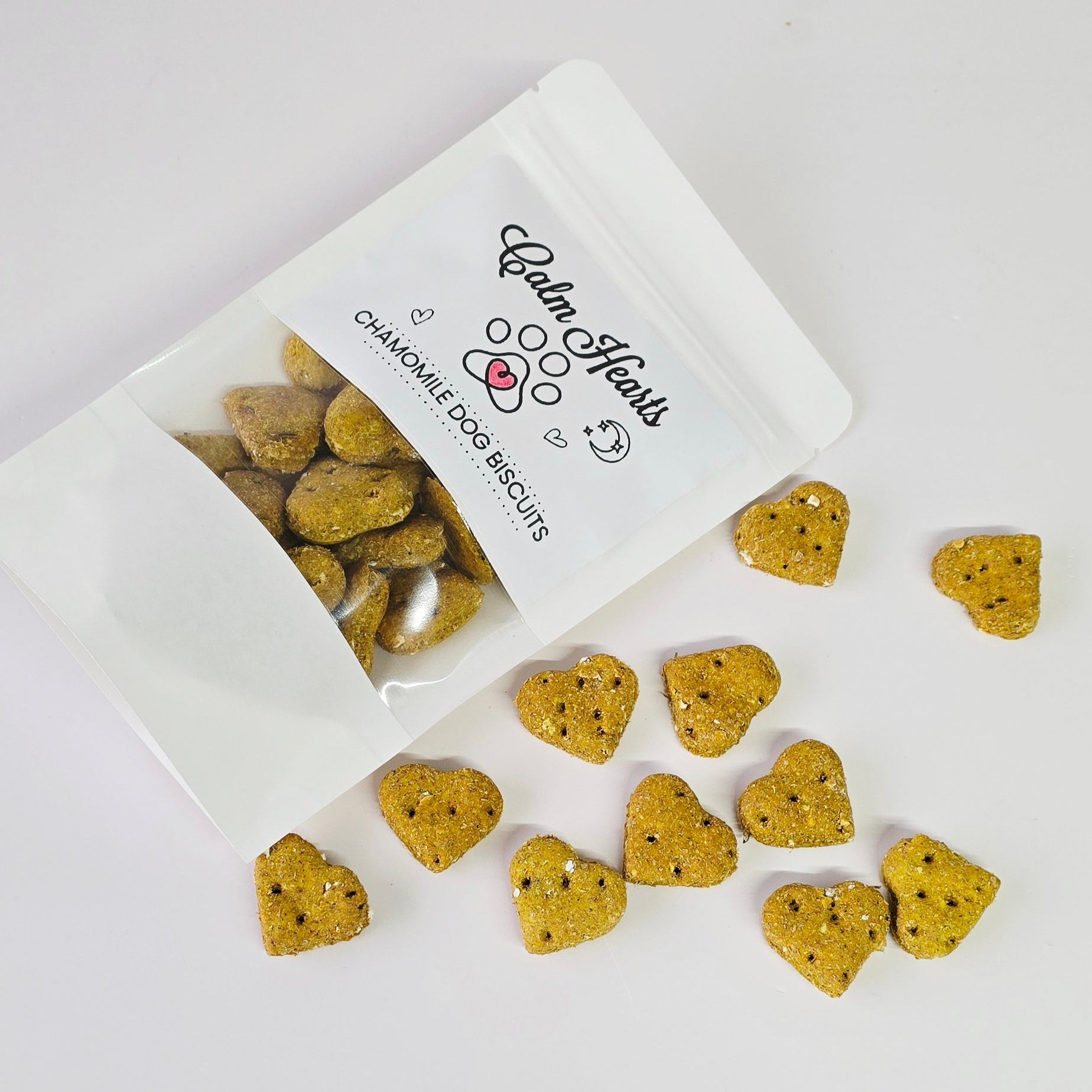 Heart-shaped dog biscuits spilling out of a white bag labeled 'Balm Hearts' on a light gray background.