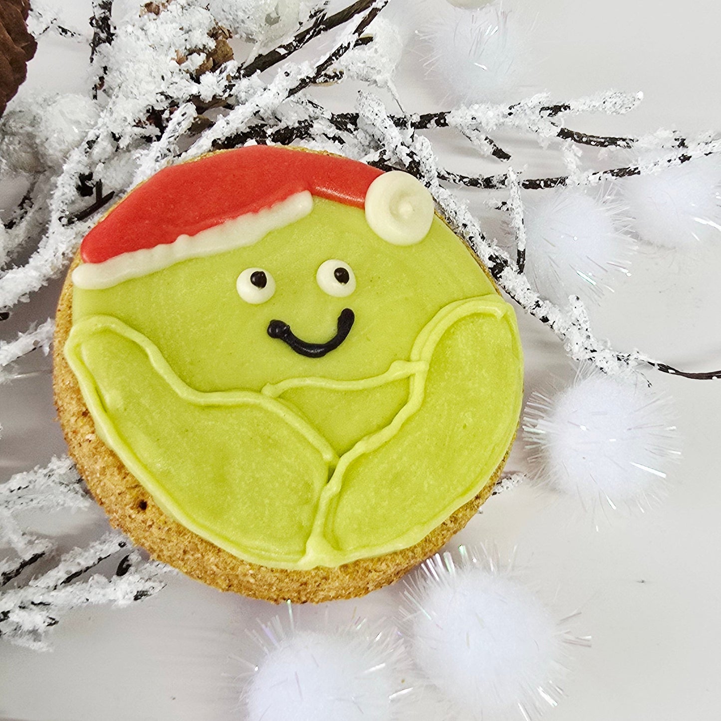Decorative cookie with green icing and a question mark on a white background with decorative elements.